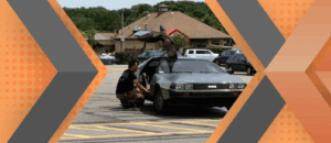 Portrait of Ben Goldsmith and his car framed by an orange and gray geometric background.